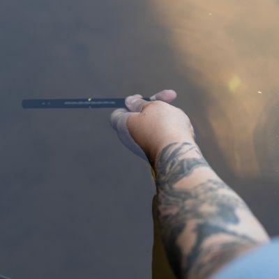 image of a person taking a river's water temperature