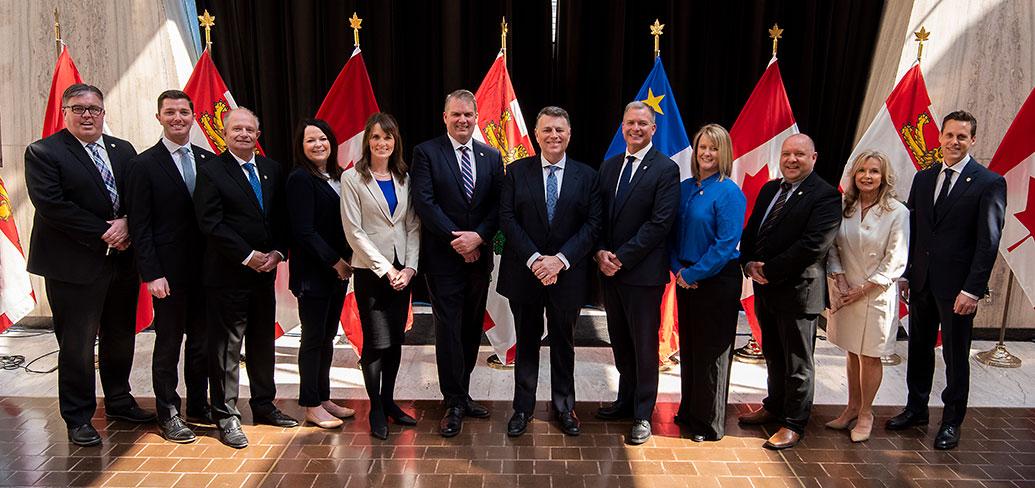 Premier King and new Cabinet members stand in front of PEI and Canada flags