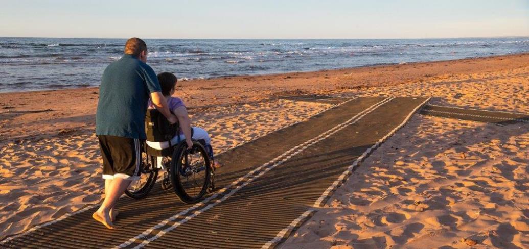 Individuals using accessibility mat on local beach