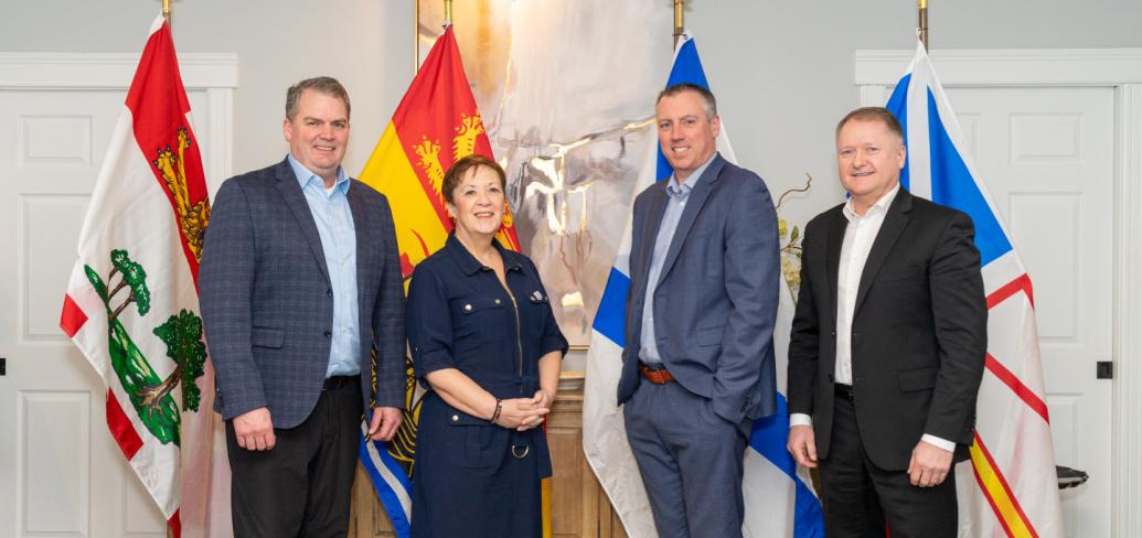 Image of 4 ministers in front of provincail flags 