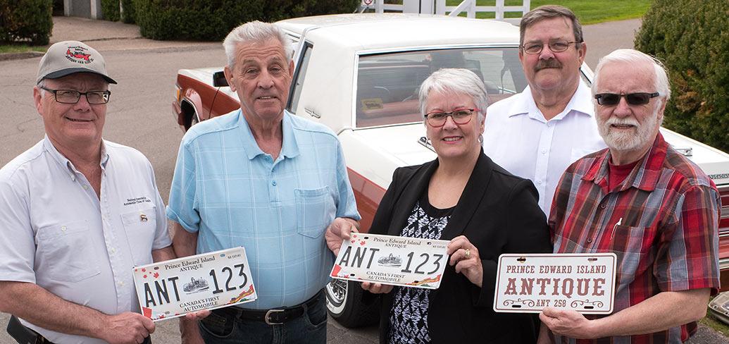 Five people holding an antiqye license plate.