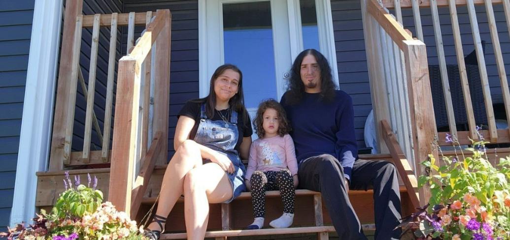 image of two adults and a child sitting on the stairs of a porch in front of a house