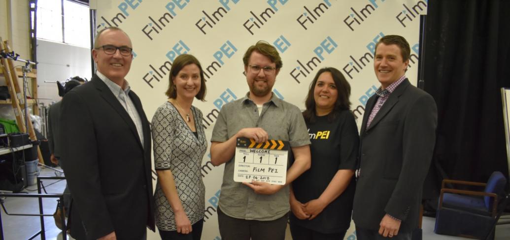 Photo shows individuals standing with a motion-picture clapboard