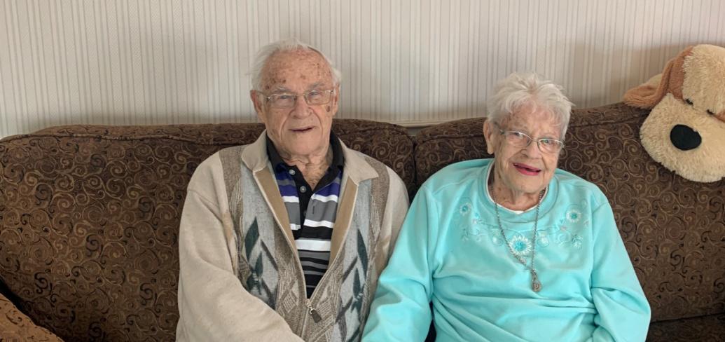 image of an older couple sitting on a couch holding hands