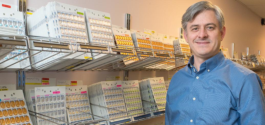 Photo shows Grant Wyand standing next to rows of medications
