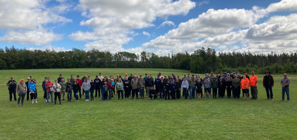 A large group of workshop participants stand outside in a field