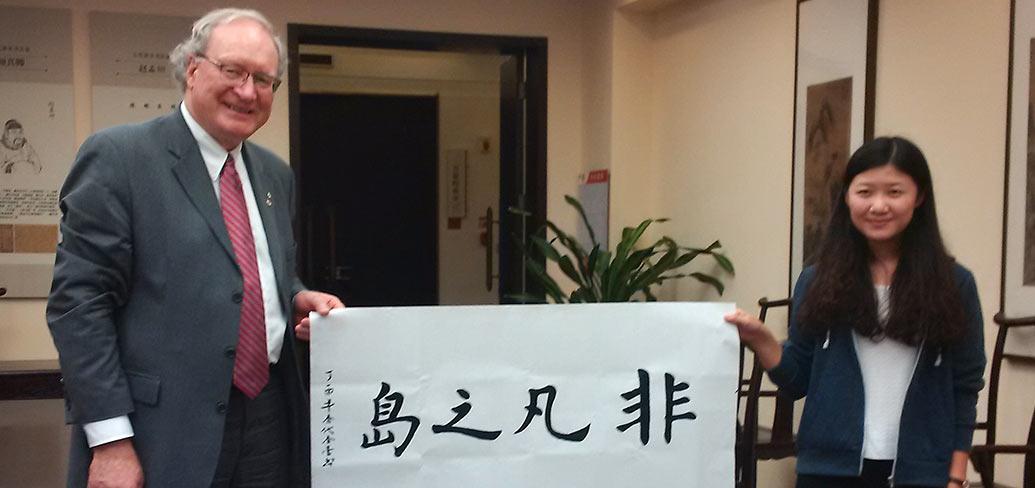 Premier MacLauchlan and  Chinese steundent hold a banner saying The Might Island in Chinese calligraphy
