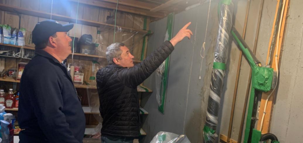Photo shows a man installing insulation in a home