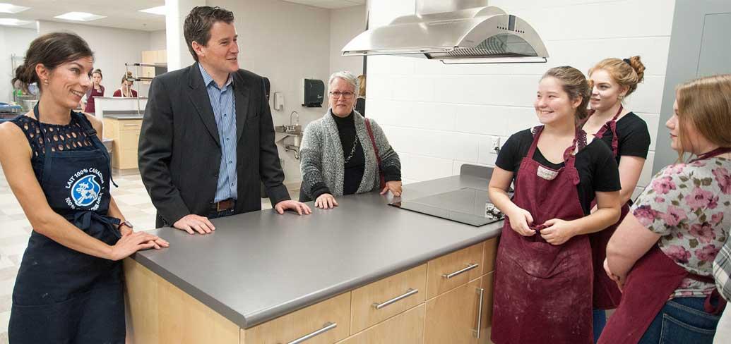 Photo shows ministers speaking with students in the newly renovated culinary arts kitchen.