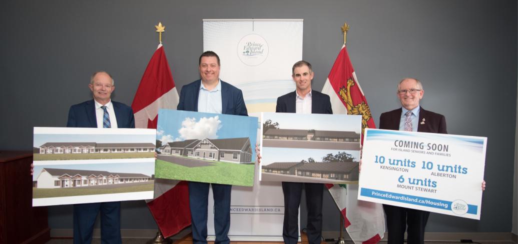 image of four people standing shoulder to shoulder holding sketches of new housing units