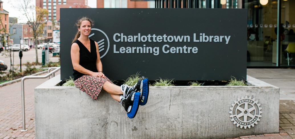 image of a person wearing ice skates and sitting bedside a sign outside a library
