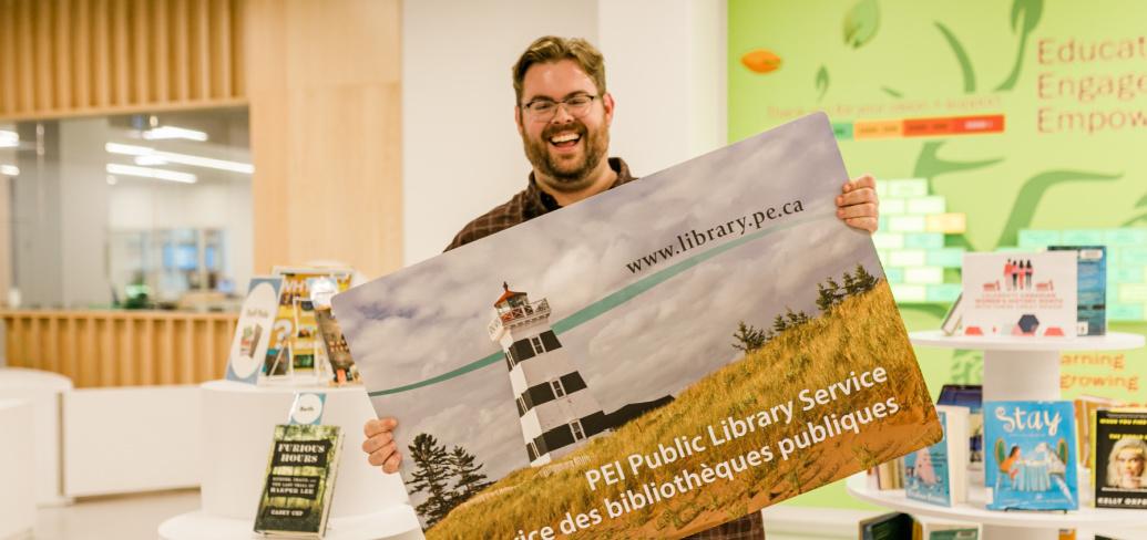 image of a person holding a large postcard with a picture of a lighthouse on it