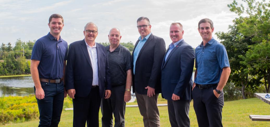 Six men stand on the bank of the Morell river following a federal provincial funding announcement
