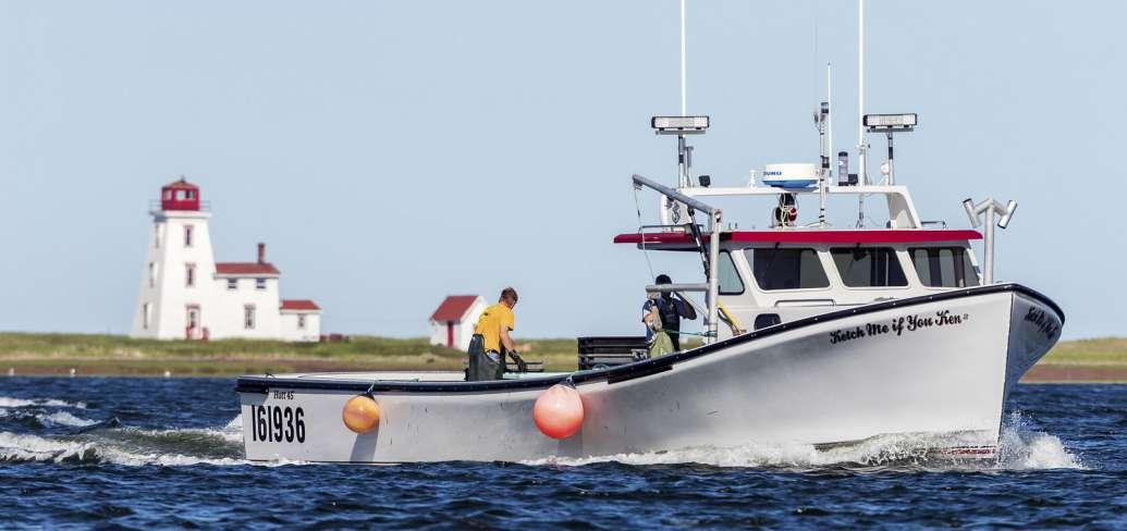 Fishing boat sails past Souris lighthouse