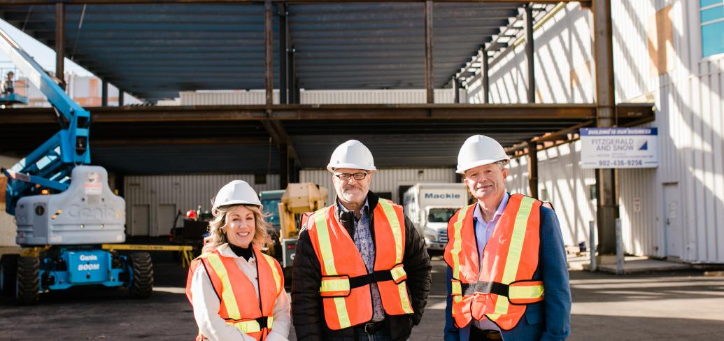 image of three people standing in front of a building construction site