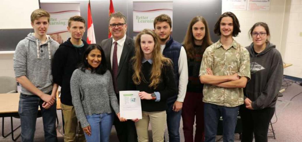 Minister Curries stands with a group of high school students