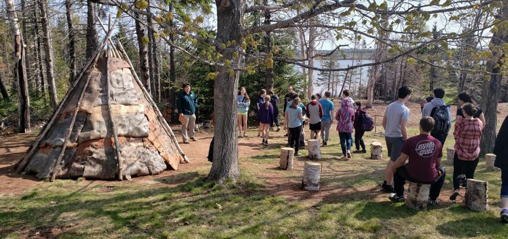 image of a group of students in the woods near a teepee
