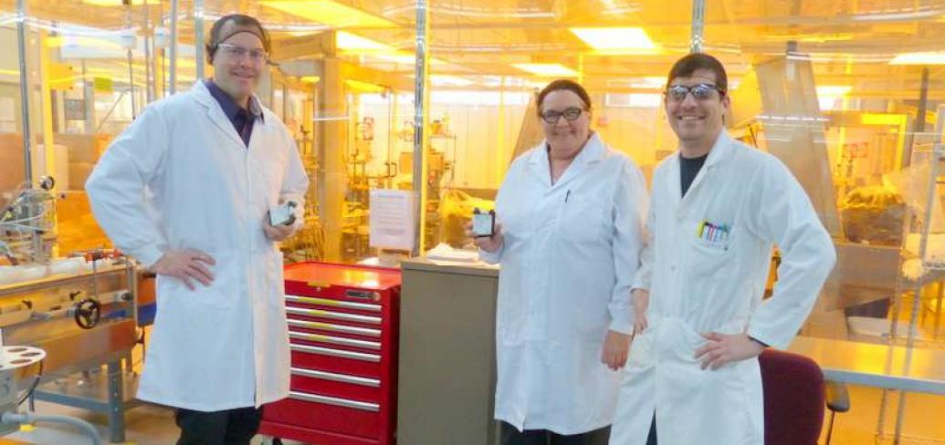 Group of three employees in lab coats display product