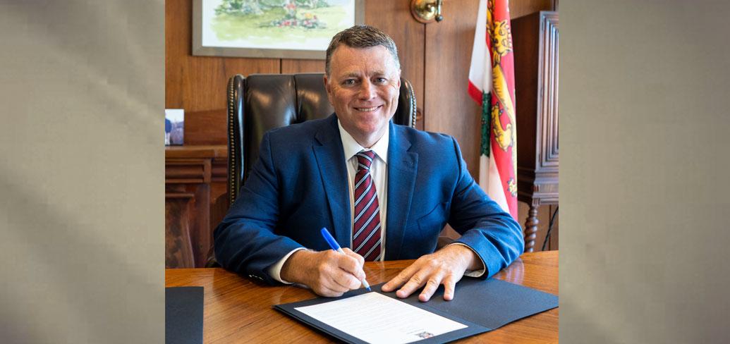 image of a man sitting at a desk signing a document