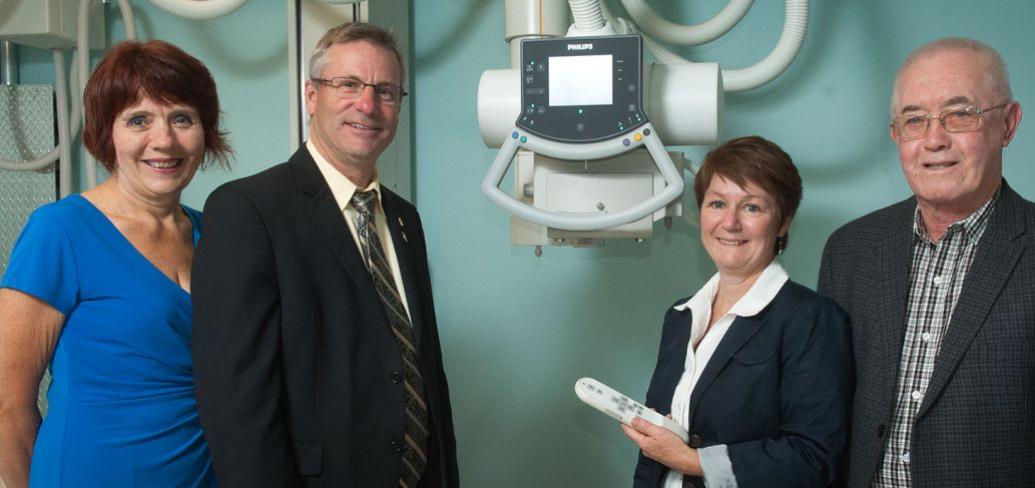 Minister of Health and Wellness, Robert Henderson and three people stand n front of a diagnostic imaging machine.