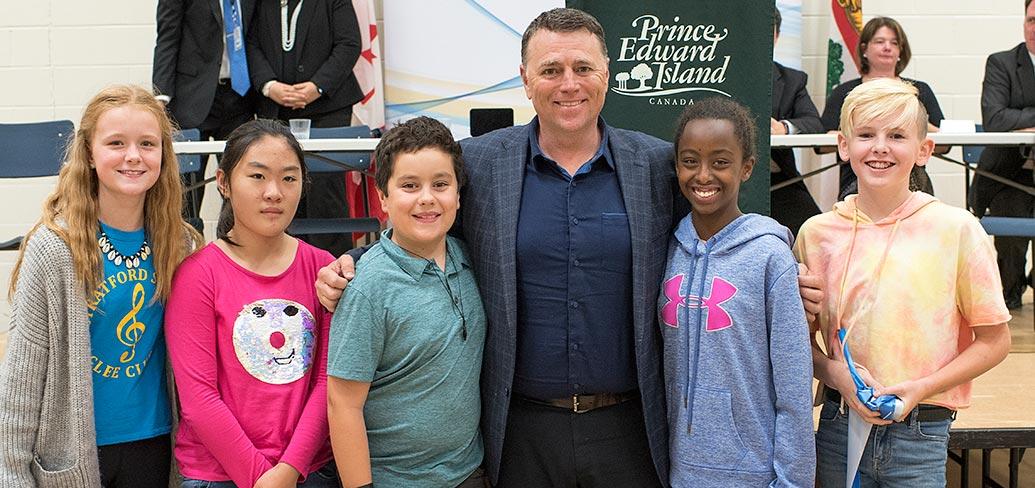 Premier King and some children standing shoulder to shoulder in front of some tables
