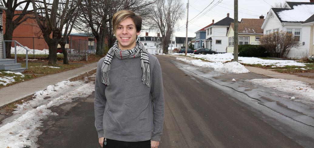 Tyler Murnaghan stands alone on a snowy city street smiling at the camera.