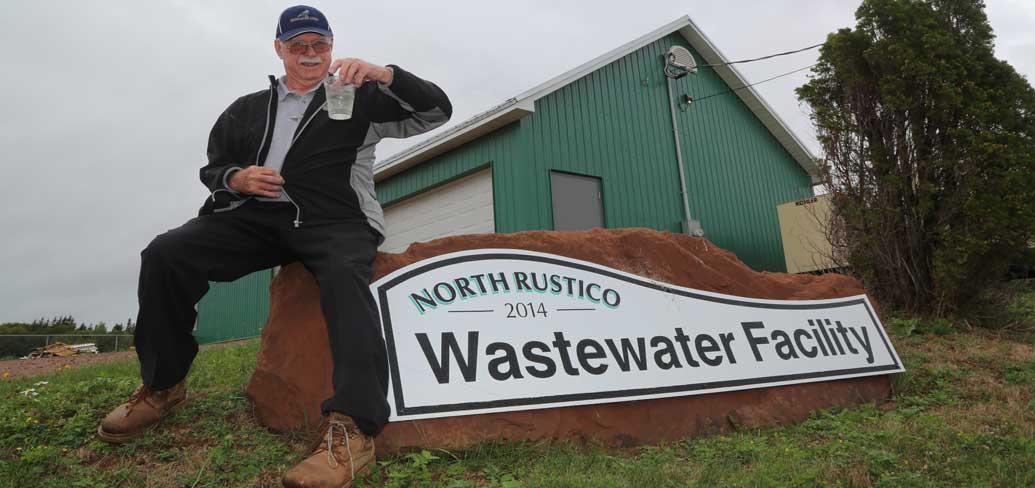 Les Standen holds a clear glass of Rustico's treated wastewater
