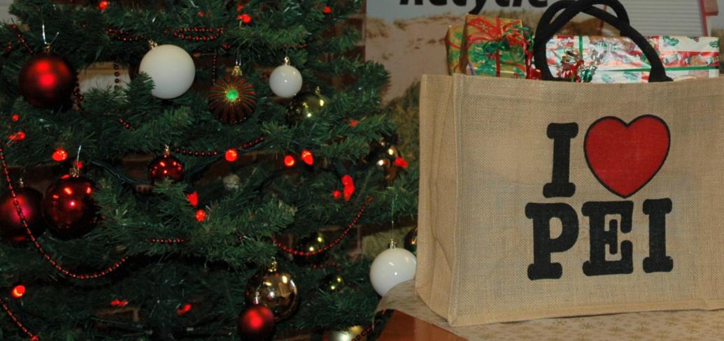 a Christmas tree beside with a shopping bag full of wrapped gifts