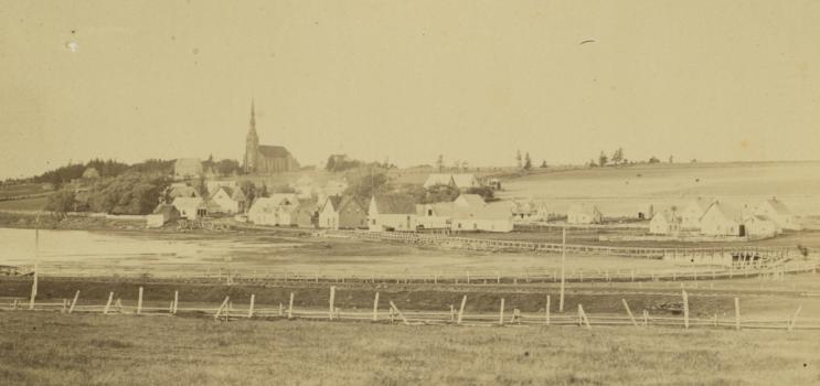La communauté de St. Peters,à l’Île-du-Prince-Édouard,vers 1870-1880. On peut voir un pont de bois surplombant la baie de St. Peters,une église en arrière-plan,plusieurs bâtiments et structures,ainsi qu’une petite embarcation dans le coin gauche inférieur