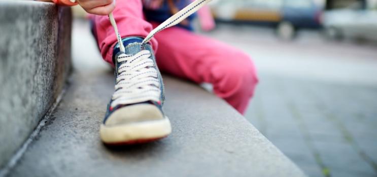 Image of small child tying shoe laces