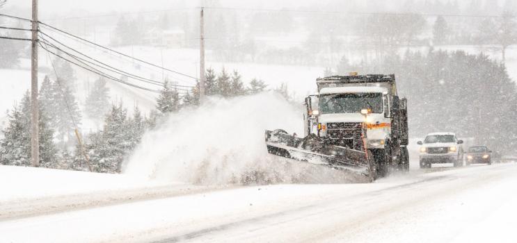 a large snowplow is plowing an Island highway