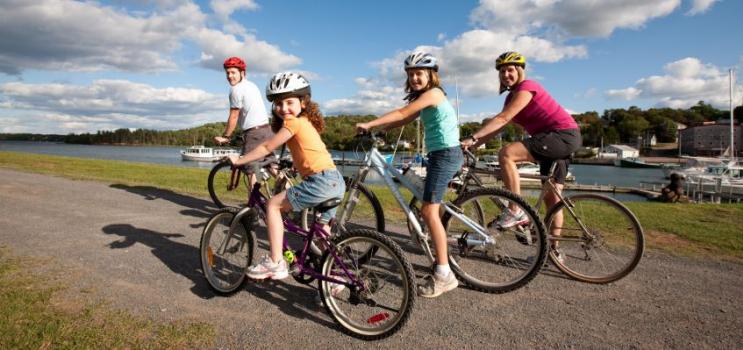 Family of four wear bicycle helmets on Confederation Trail