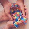 Four hands holding ribbon representing autism