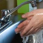 A person washing their hands under a running faucet