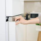 A hand opening a refrigerator. 