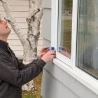 Male home energy inspector takes a reading at a picture window