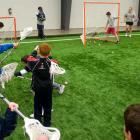 Group of school children learning to play lacrosse