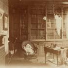 Photograph of an unidentified study or library room showing a wall lined with bookcases, [ca. 1890-1906]