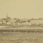 Community of St. Peters, Prince Edward Island, ca. 1870-1880. A wooden bridge across the St. Peters Bay can be seen, as well as a church in the background. Several other buildings and structures are also visible. A small boat is in the lower left corner.