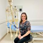 A woman, a physiotherapist, poses in front of a skeleton 