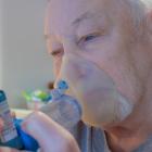 An older man uses an inhaler