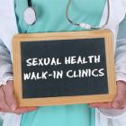 Health Care Professional holding a sign that says: Sexual Health Walk-in Clinics