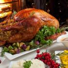 Image of dinner table set with roasted turkey, mashed potatoes, cranberry sauce and pickles