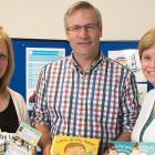 Three people standing together displaying baby books