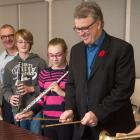 Minister Doung Curie and Music Teacher Frank Nabburs and four students hold musical instruments