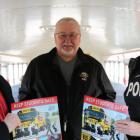 Three people stand inside a school bus holding school bus safety posters
