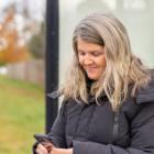 image of a person at a bus stop looking at her cell phone