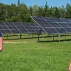 image of two people standing in fron of some solar panels with trees in the background