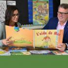 Teacher and Minister of Education sit in a classroom looking a new resource book