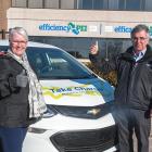 Four people stand beside an electric car in front of the efficiencyPEI building